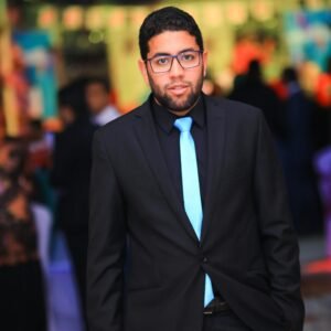 Portrait of a young man in a suit at a vibrant indoor event with bright decor.
